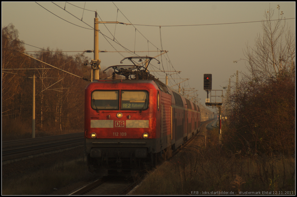 Bei tiefstehender Novembersonner fährt DB Regio 112 109 mit dem RE2 nach Rathenow am 12.11.2011 in dem Bahnhof Elstal (Wustermark) ein.