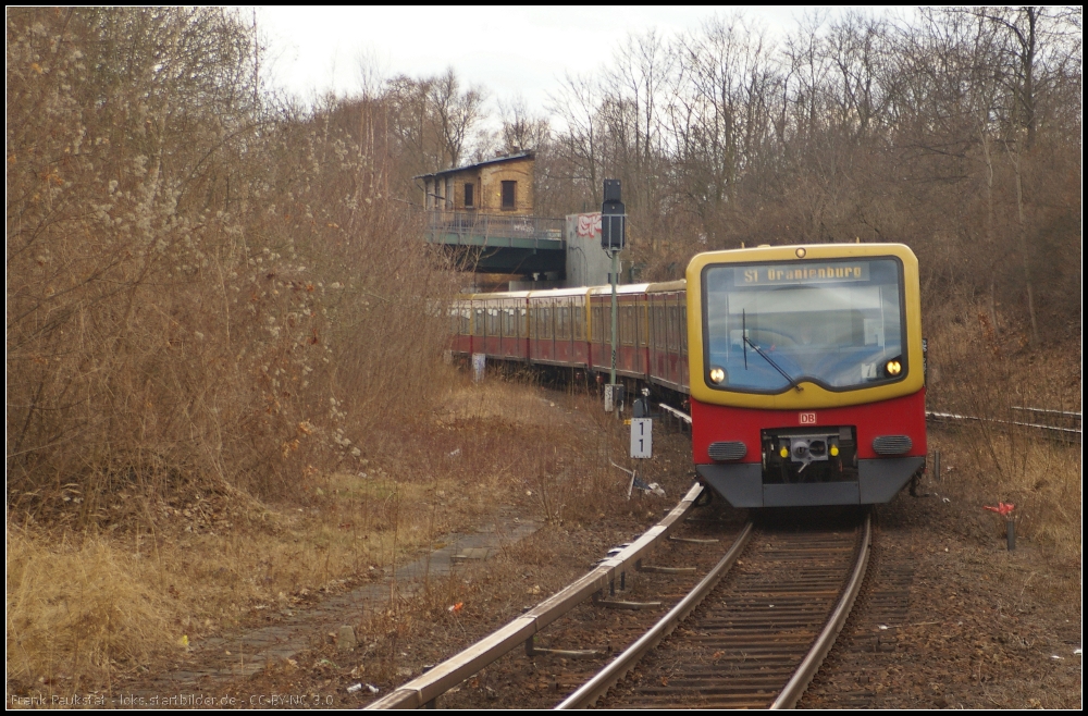 Ein Zug der Linie S1 nach Orainienburg der Berliner S-Bahn bei der Einfahrt in den Bahnhof Humboldthain. Im Hintergrund das ehemalige Stellwerk Ntm, das für die Signale und Weichen des ehemaligen Stettiner Bahnhofs zuständig war