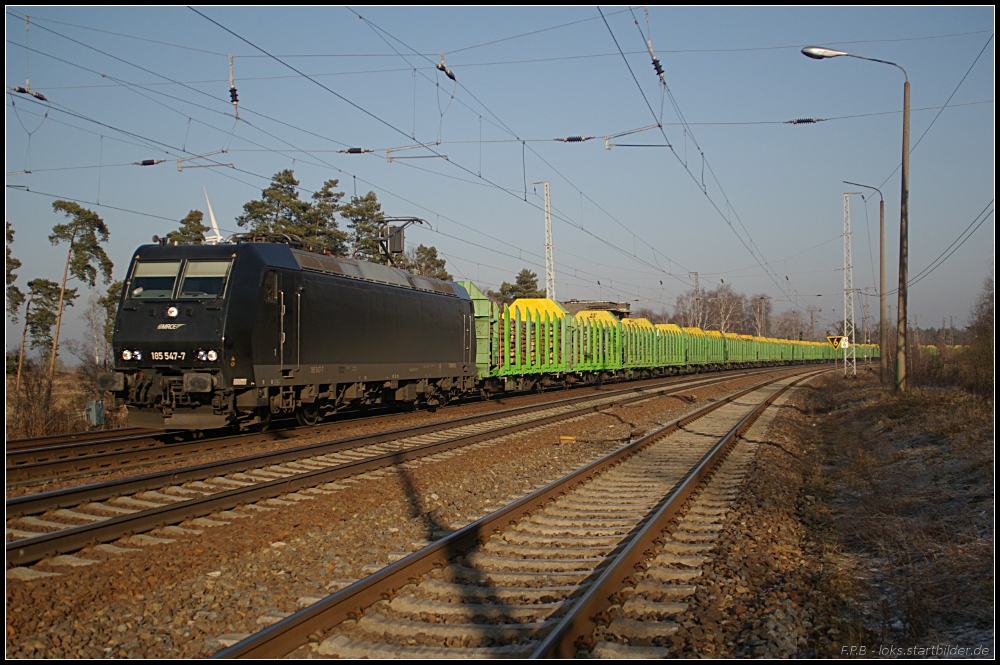 Fr PRESS ist 185 547-7 mit reichlich Holz unterwegs. Hier durchfhrt sie am 29.01.2011 den Bahnhof Friedrichsfelde-Genshagener Heide.