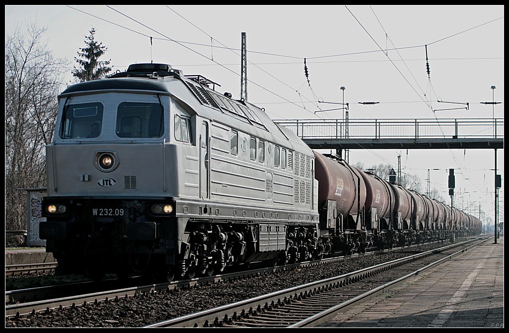 ITL W 232.09 kommt aus dem Gegenlicht mit einem Kesselzug durch den Bahnhof (ex GATX, ex Bombardier, ex EBG, ex SZD TE 109 026, gesehen Wustermark-Priort 25.03.2010)