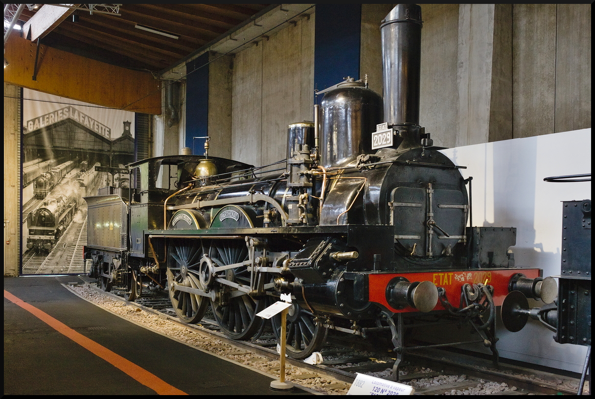 Aus den Anfangsjahren stammt die ETAT 2029, gebaut von Schneider & Cie aus dem Jahr 1882 mit der Fabriknummer 2122. Wie das Schaubild im Hintergrund suggeriert sind diese Loks vom Typ 120 niemals von Galeries Lafayette gefahren. Nach der Umnummerierung war sie die SNCF 3-120 A 36. Im Einsatz war die Lok bis ins Jahr 1947. Inzwischen steht sie im Eisenbahnmuseum Cite du Train in Mulhouse und wurde am 10.11.2023 fotografiert.