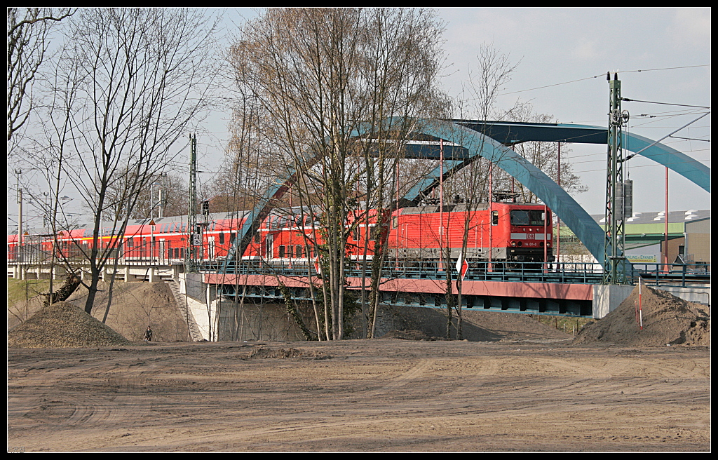 DB Regio 114 011-0 mit dem RE1 überquert die neue Brücke direkt hinter dem neuem Regionalbahnsteig. Die Sandfläche im Vordergrund wird ein Parkplatz (Erkner 06.04.2010)